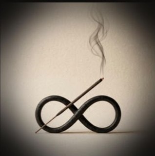 Burning incense stick resting across a black infinity-shaped holder